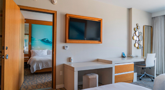 view of connecting rooms with a mounted tv and desk and in the backroom a bed.