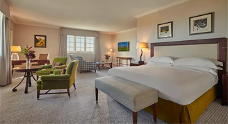 Image of the Deluxe Sea Suite with one bed, seating are and adjacent window.