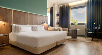 A king bed with a seating area next to a large window.