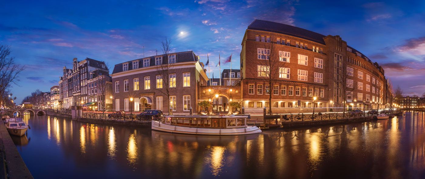 A view of the hotel's entrance from across the waterway at night.