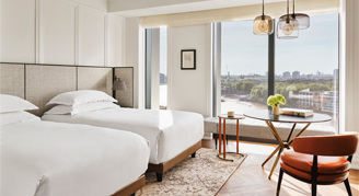 Image of two beds by a large window in a River-View Room.