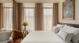 Photo of hotel room with bed and large windows.