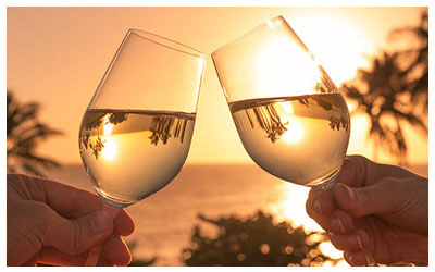 Image of a honeymoon toast during a tropical sunset.
